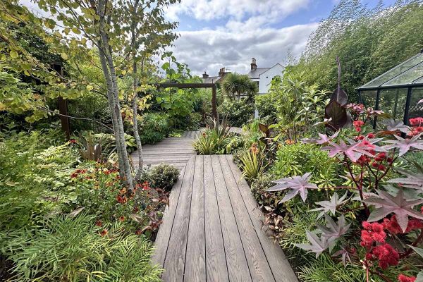 Antique Oak Millboard Decking edges pool with goldfish. Hedging runs down side of lawn towards house. Design by Shoots and Leaves.***Shoots and Leaves, www.shootsandleaves.co.uk