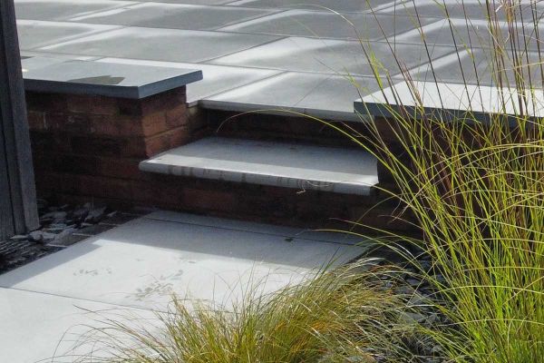 Close up shot of Florence Storm Porcelain 36mm Bullnose step leading up to wet patio in the same material.***Monarch Lawn & Landscape, www.monarchlandl.co.uk