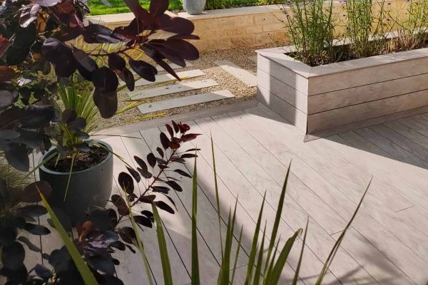 Designed by April House Garden Design www.april-house.co.uk | Built by EWB Services
View through foliage shows Cinnamon DesignBoard Composite Decking used on patio area and clad around built in flowerbeds.***Designed by April House Garden Design www.apri