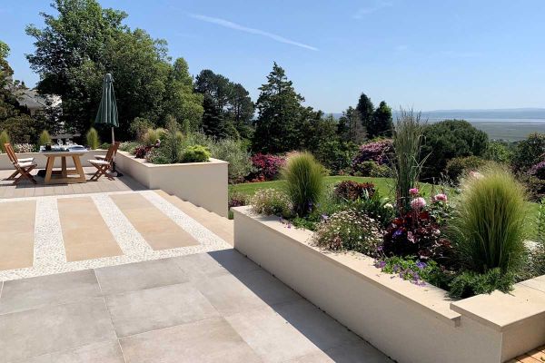 Countryside views seen from multi level garden with deck and patio, steps lead down to lawn with raised flowerbeds using harvest coping stones.***Botanica Garden Design, www.botanicagardendesign.com
