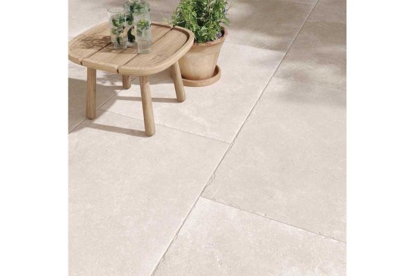 Light-toned Heritage Chalk Premium Italian Porcelain Paving with soft stone texture, shown with a wooden table and potted plant.***