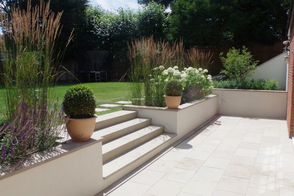 4 buff sawn sandstone steps lead from matching patio up to lawn area, rendered walls with built-in flowerbeds surround.***Kiwi Landscapes,  www.kiwilandscapes.com
