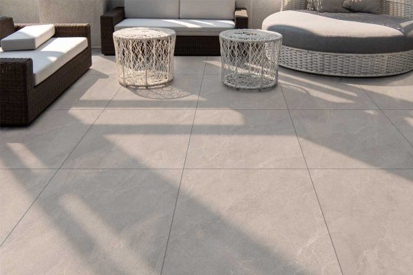 Modern outdoor space using Piazza Grey Porcelain Paving, with rattan garden furniture and smooth tiles in a soft grey tone.***
