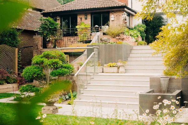 Blurred view through foliage show impressive outdoor staircase using kandla grey porcelain 20mm bullnose steps and matching paving.***Gardenscapes