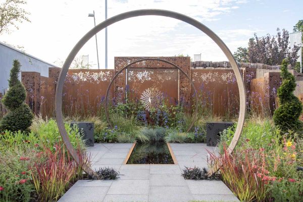 Dark Grey Granite paving with grassy planting in Sunburst Garden, RHS Hampton Court 2022 by Charlie Bloom and Simon Webster.***Design by Charlie Bloom & Simon Webster | Built by HCDreamTeam.co.uk, mentored by Burnham Landscaping & London Stone