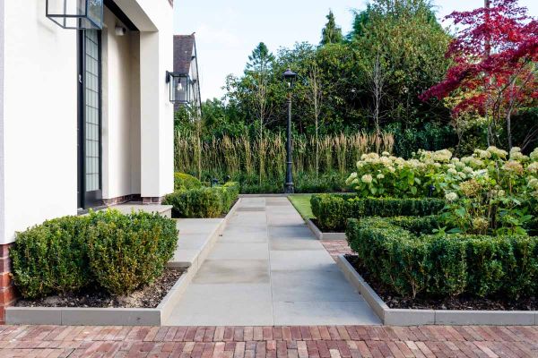 Path of Heath Sandstone adjacent to clay paver patio, leads through hedges to front door, flanked by Heath Edging Stones.***Robert Hughes Studio, www.roberthughesgardendesign.co.uk
