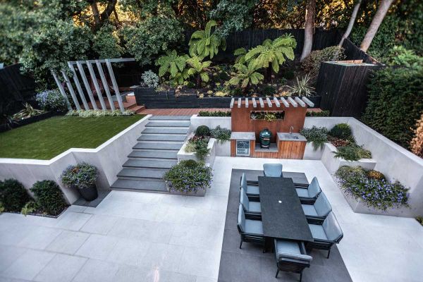Steel Grey porcelain steps with white flanking walls rise from light paving to deck and lawn area. Design by Gardens of the Future.***40mm Downstand | Gardens Of The Future
