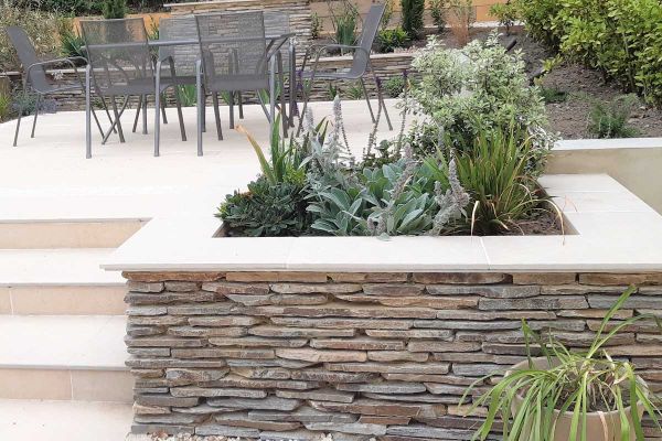 Stone clad raised wall turned planter used florence beige porcelain 5mm chamfered coping stones with matching paving on patio.***Anna Helps Garden Design, www.annahelpsgardendesign.co.uk

