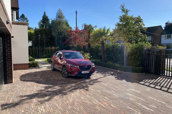 Red Mazda sits on broad driveway across front of house. With gate, hedge and Bexhill clay pavers in running bond pattern.***Robert Hughes Garden Design, www.roberthughesgardendesign.co.uk