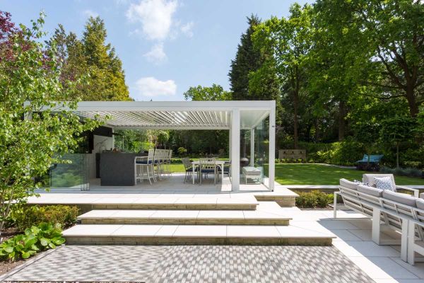 2 wide wrap-around Florence White bullnose porcelain steps rise to matching patio with large white pergola over outdoor kitchen.***Barnes Walker Ltd, www.barneswalker.co.uk