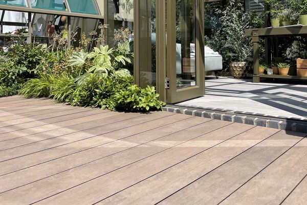 Greenhouse with doors open onto Chestnut Brushed DesignBoard edged by foliage. Design by Llevelo. Built by Stewart Landscape.***Also shows Travertine Dark Porcelain | Built by Stewart Landscape for Hartley Botanic | Design by Llevelo Garden Design