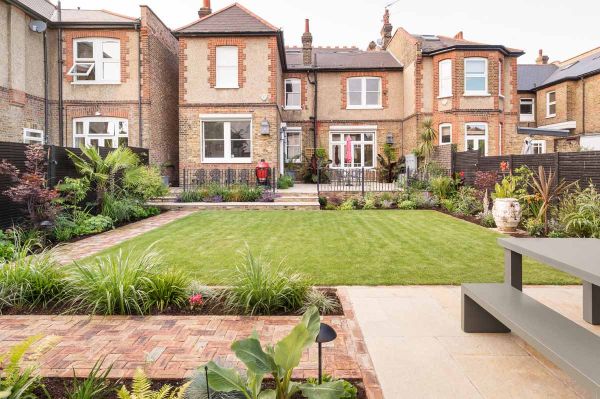 Cotswold clay paver path, between lawn and long border with architectural plants, leads from patio to brick-paved area with beds.***Kiwi Landscapes,  www.kiwilandscapes.com | Simon Callaghan Photography
