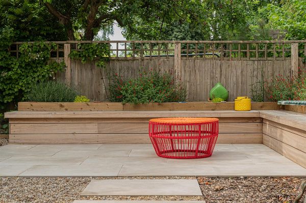 Back garden L shaped bench constructed from hard wood timber sitting on top of a Cream porcelain paving patio.***Hythe Garden Landscapes, www.hythegardenlandscapes.co.uk