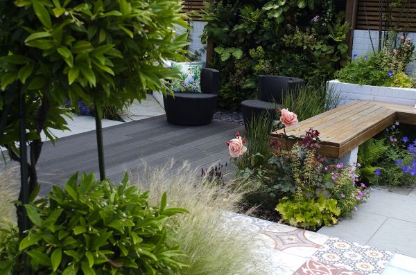 Charcoal composite outdoor decking laid with decorative tiles in garden with topiarised laurel, living wall and brick raised beds.***Botanica Gardens,  www.botanicagardendesign.com