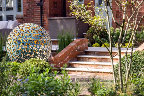 Large circular metal structure at the end of set of Egyptian Beige Limestone Bullnose steps. Mowtivated see garden step ideas come to life.***Mowtivated, www.mowtivated.co.uk | Photos by www.skyshotglobal.com