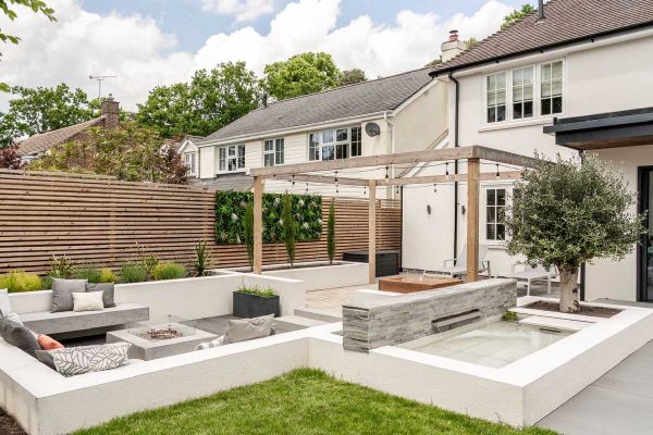 Low wall of Kandla Grey sandstone external cladding backs raised pond next to olive tree, adjacent to sunken seating area.***Gadsden Gardens, www.facebook.com/GGLandscapers
