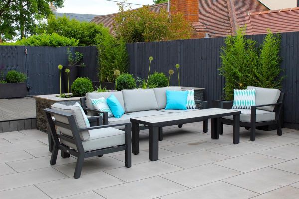 Metal lounging set in a rear back garden paved with Polished Concrete porcelain in front of a raised composite decking area.***Essex Garden Designs,  www.essexgardendesigns.co.uk