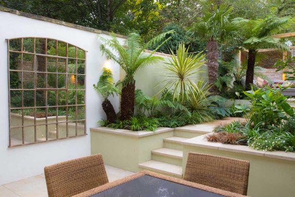 Golden Stone flat coping stones top white-rendered retaining walls in garden that rises from patio of matching paving.***Designed by Urban Paradise Garden Design, www.urbanparadisecompany.com | Built by Tony Djouklev of SDTony Building Services | Photos b