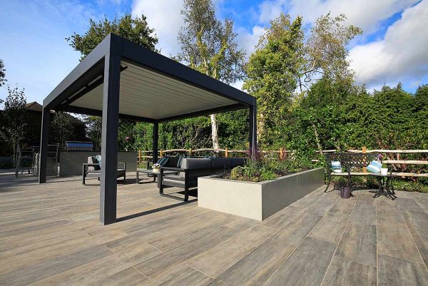 Large rectangular raised bed faced with Hydra Plomo external porcelain cladding next to metal pergola and outdoor furniture.***Designed by Karen McClure, www.karenmcclure.co.uk Built by Esse Landscapes, www.esseland.co.uk
