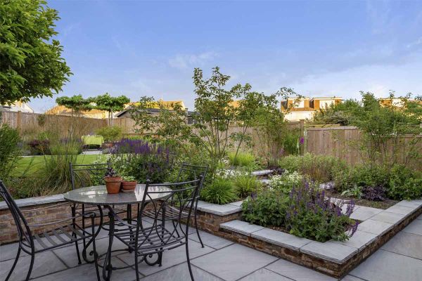 Kandla Grey Indian Sandstone paves garden patio with metal furniture. Matching coping tops retaining walls of adjacent raised beds.***Designed by Bob Richmond Watson Landscape & Garden Design,  www.bobrichmondwatson.com  |  Built by Acacia Gardens,  www.a