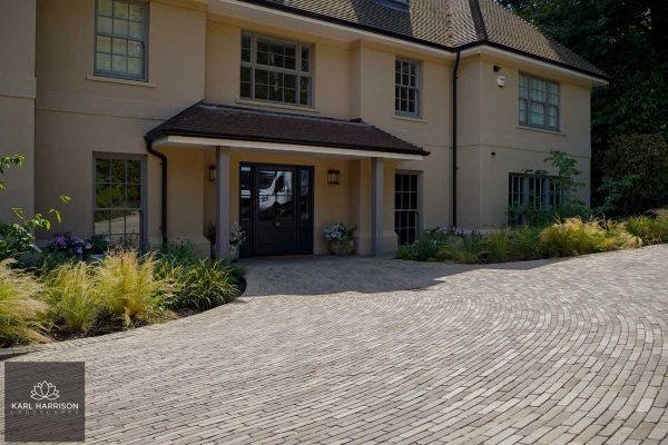 Wide drive of Gromo Antica brick pavers laid in curved pattern in front of house in deep shadow. Design by Karl Harrison.***Karl Harrison Landscapes, www.karlharrison.design
