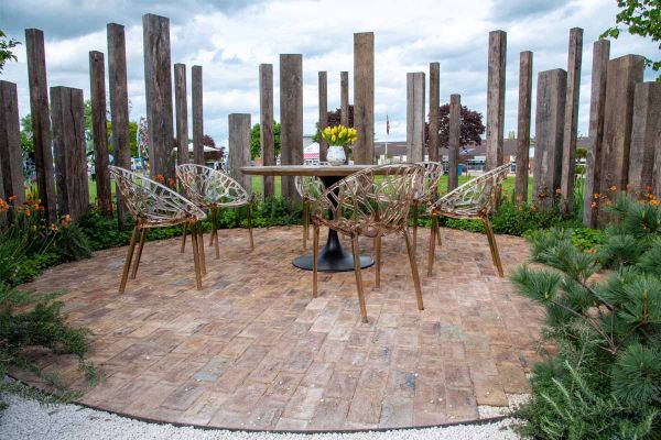 Outdoor furniture on paving circle of London Mixture Belgian Bricks, with wooden monoliths behind. Built by Landform Consultants.***Designed by Alan Williams, www.landformconsultants.co.uk | Built by Landscapia,  www.landscapia.co.uk