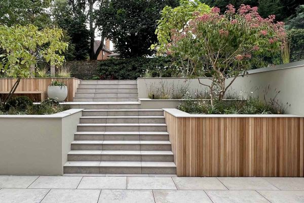 Jura Grey outdoor steps, flanked by trees in beds, rise in 2 consecutive flights from paving to upper garden level.***Tom Howard Garden Design, www.tomhowardgardens.co.uk
