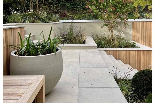 Large pot on landing of Jura Grey porcelain outdoor tiles uk that interrupts matching steps which rise between deep raised beds.***Tom Howard Garden Design, www.tomhowardgardens.co.uk
