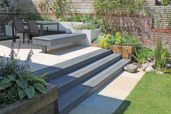 3 steps of Millboard bullnose rise between wooden sleeper beds to patio with matching inbuilt bench and dining set in walled garden.***Brushed Basalt Bullnose Boards | Design, Build & Photography by Outerspace Creative Landscaping, www.outerspacegardens.c