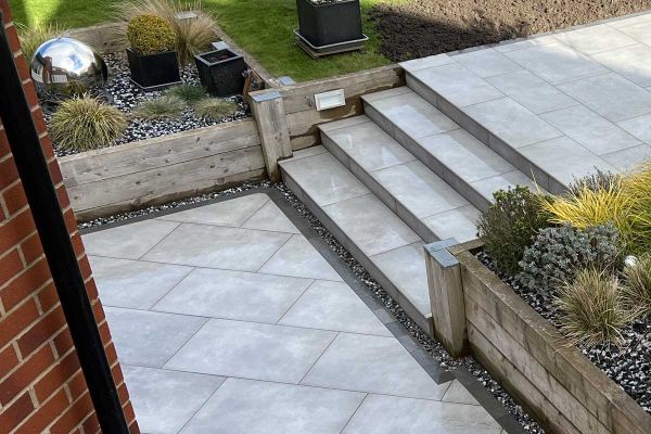 4 steps descend between wooden raised beds to paved area edged with Platinum Grey small porcelain patio tiles.***Instant Scenery, www.instantscenery.co.uk
