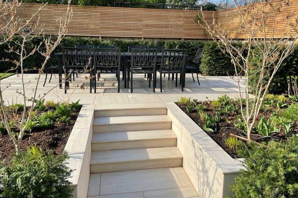 Faro Porcelain smooth coping tops flank walls of steps up to patio with dining set and neat  hedging. Design by Shoots and Leaves.***Shoots and Leaves, www.shootsandleaves.co.uk