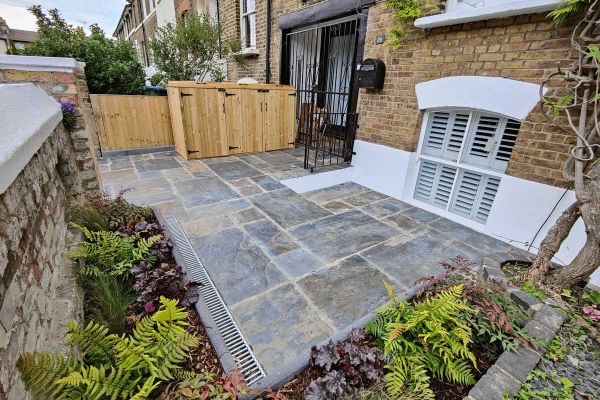 View from front of house showing Rustic Slate Paving leading to bin store next to gated french doors, flowerbeds surround.***Katerina Kantalis Garden Design, www.katerinakantalis.co.uk

