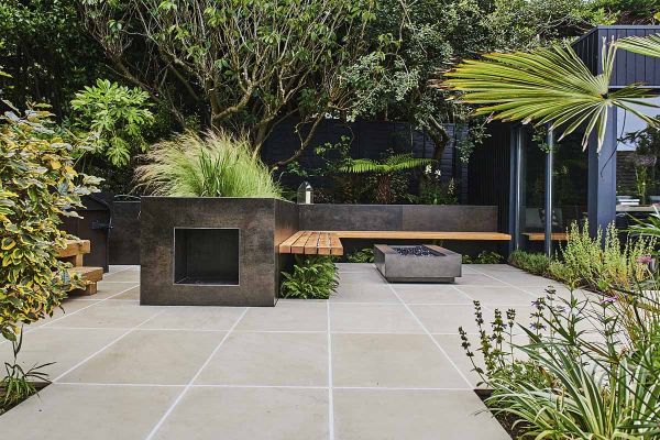 Steel Dark DesignClad porcelain cladding faces an L-shaped raised bed with attached benching. Ferns planted beneath bench.***Image also displaying Beige Smooth Sandstone Paving | Amanda Lorenzani Garden Design,  www.amandalorenzanidesign.com

