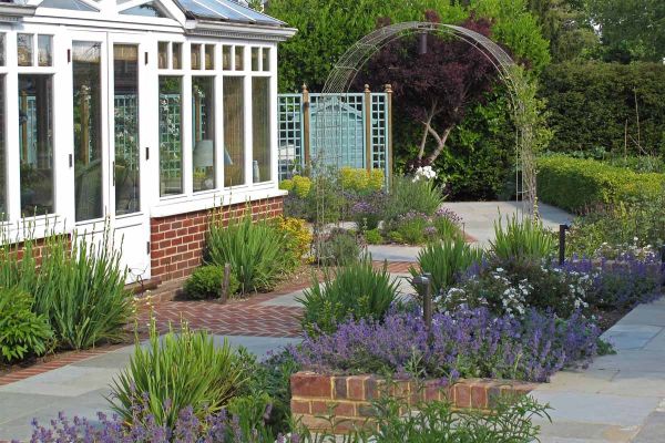 Kota Brown stone  paving and clay pavers laid on 2 levels outside conservatory, with clipped hedging, lavender and a rose arch.***Cherry Mills Garden Design, www.cmgardendesign.com

