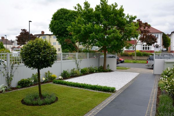 Midnight Black limestone stone paving, edged with setts, slopes up past 2 large squares of white gravel and lawn in front garden.***Tom Howard Garden Design,  www.tomhowardgardens.co.uk
