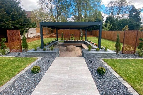 Travertine Dark Porcelain Paving used as path heading towards dark pergola with sunken deck surrounded by planting.***Landscapia Garden Design & Build, www.landscapia.co.uk