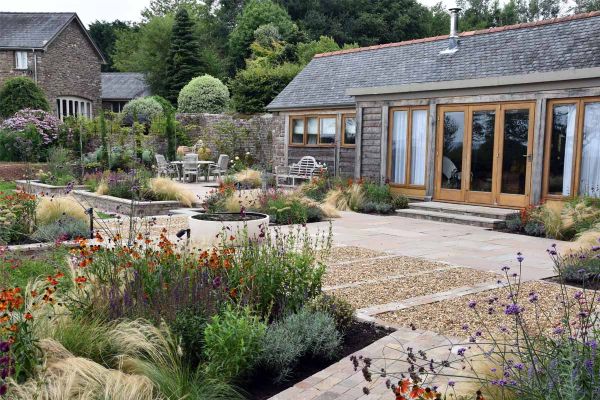 Huge studio with 2 steps down to paved area of Tumbled Raj Green sandstone garden paving slabs and gravel punctuated by raised beds.***Designed by Lisa Cox Garden Designs,  www.lisacoxdesigns.co.uk  | Built By Jamie Morgan General Builder