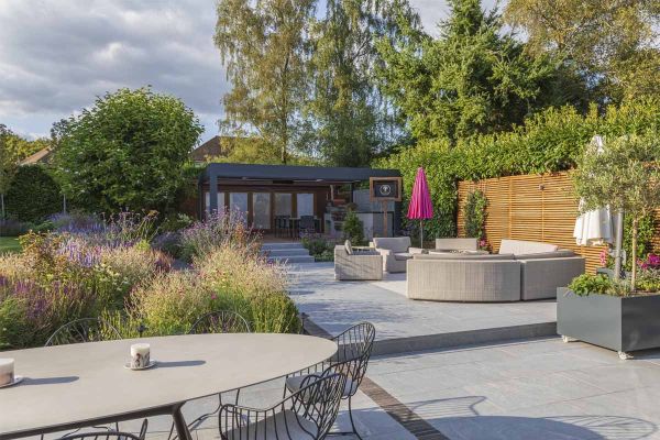 Large Versilia Porcelain patio with luxury outdoor furniture. Steps up to pergola. Prairie planting to left. Built by J & S Scapes***Design by Chiltern Garden Design, www.chilterngardendesign.com | Built by J&S Scapes, www.jands-scapes.co.uk