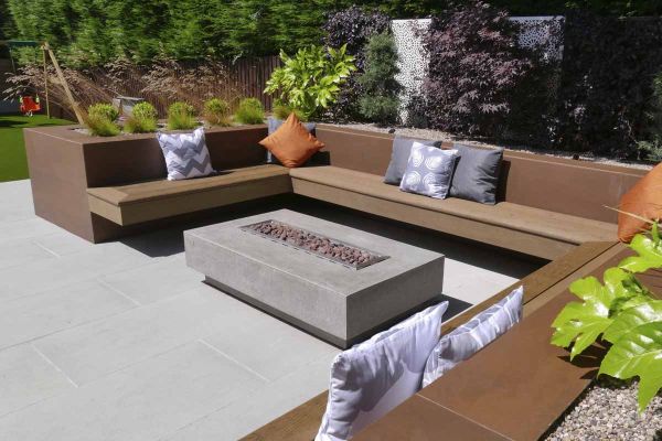 Firepit sits in the middle of a floating bench sat on patio, raised walls surround clad with vintage steel premium designclad.***Landscapia Garden Design & Build,  www.landscapia.co.uk
