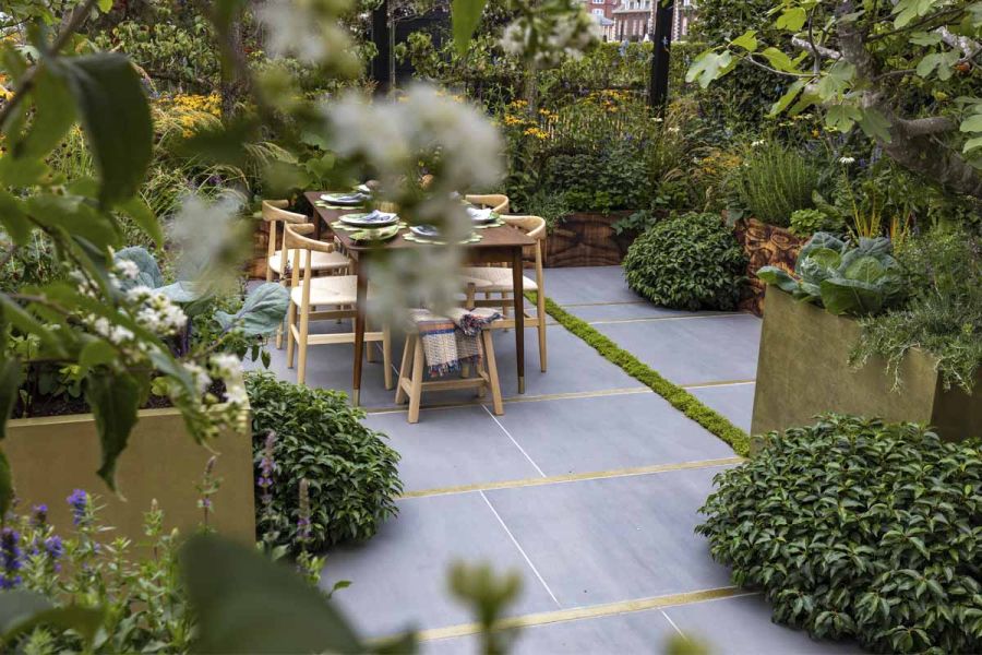 Garden dining area surrounded by lush extensive planting and surfaced with 1200x1200 Sidewalk porcelain slabs.