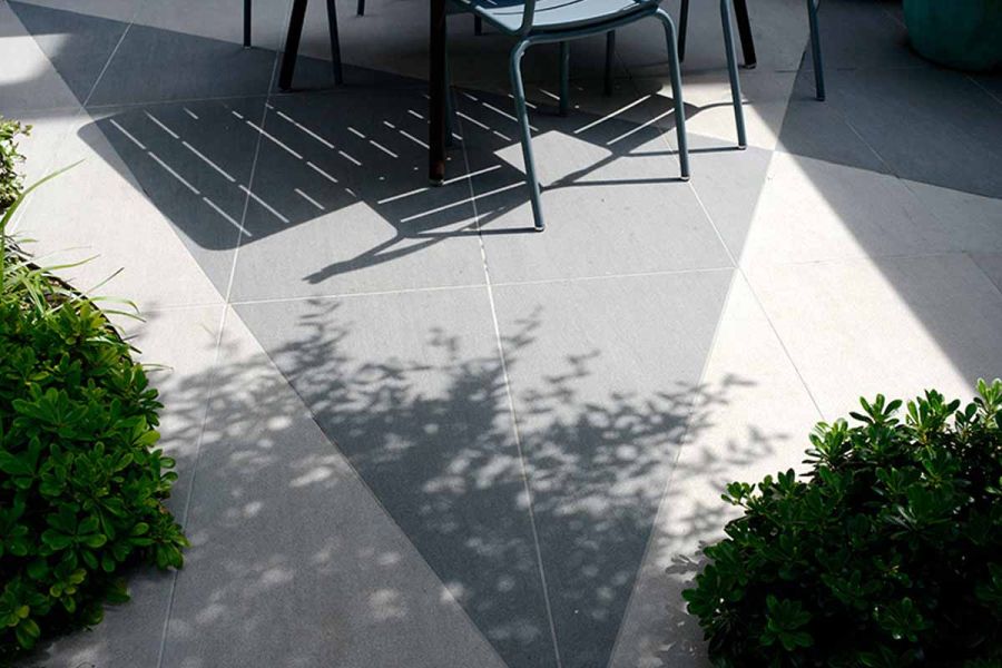 Mesmerizing shadows dance across slabs, illuminated by  gentle rays of natural sunlight, enhancing the trendy black and urban grey porcelain tiles.