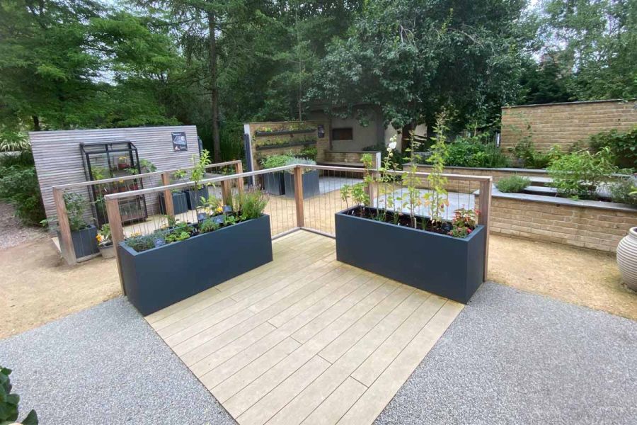 Amber DesignBoard composite decking laid with resin-bonded gravel and hoggin in easy-access planting areas of raised beds.