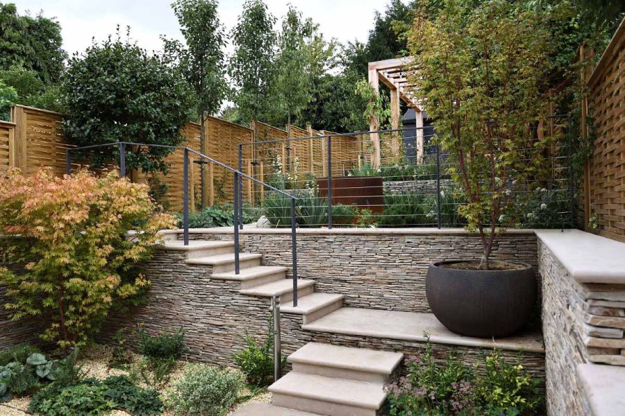 A lush garden setting showcasing Jura Beige bullnose steps and paving surrounded by vibrant greenery.