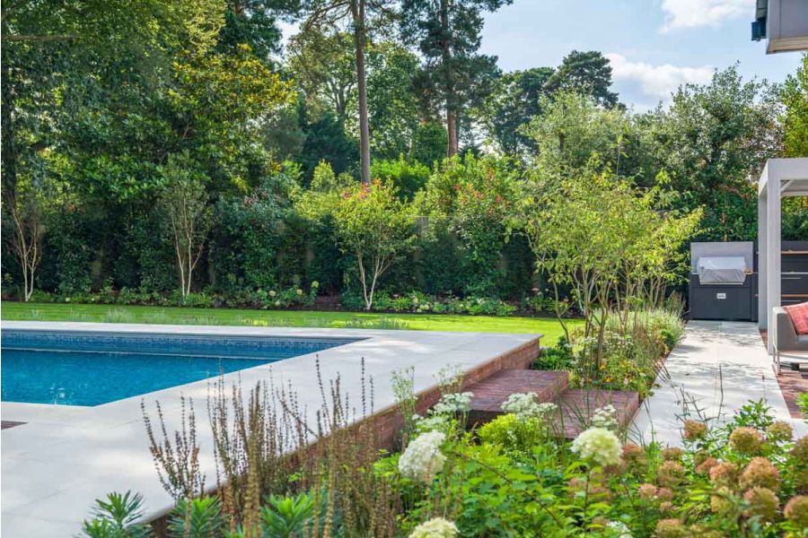 2 Antique Red clay paver steps, flanked by beds, rise from Dove Grey smooth sandstone path with matching swimming pool surround.