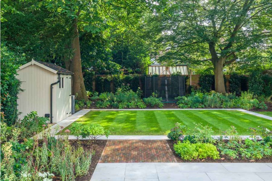Antique Red clay paving divides a planted border, connecting Dove Grey sandstone paving to matching path that surrounds lawn.