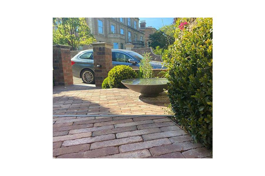 Front garden with wide water bowl and clipped shrubs, paved with Bexhill clay pavers. Georgian terrace in background.