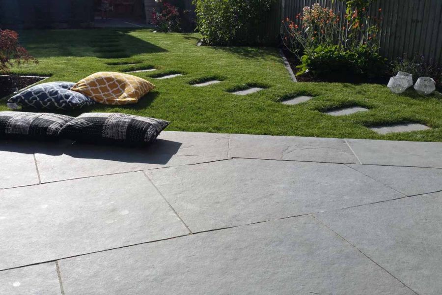 Graphite Grey limestone 9900x600 patio laid at angle to lawn, with smaller matching slabs making stepping stone path in grass.