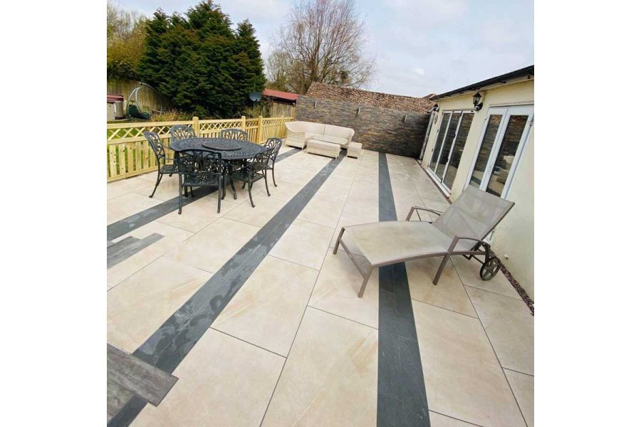 Large raised terrace in Ash Beige porcelain paving with strips of darker material breaking up the pattern.