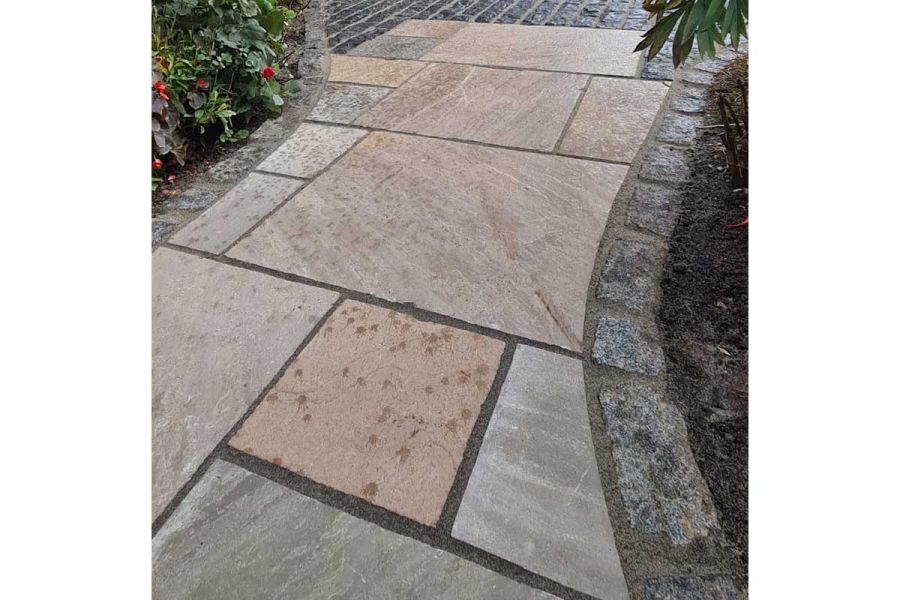 Autumn brown Indian sandstone project pack slabs with granite sets between curved planted beds. Built by Cypress garden services.
