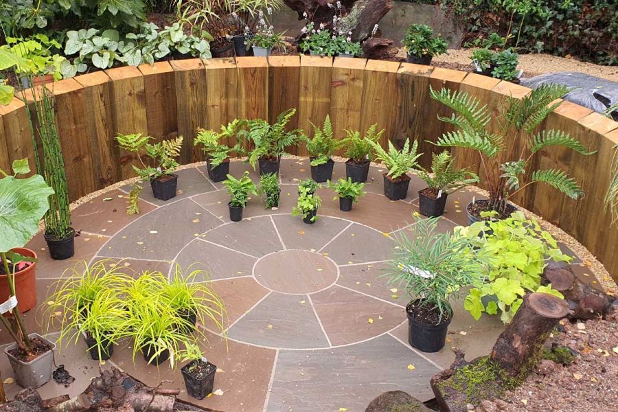 Autumn Brown Sandstone Circle edged by planting, with sinuous path leading to large wooden garden room. By No.30 Design Studio.